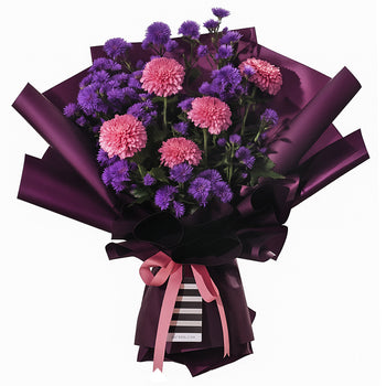 A striking bouquet featuring full pink chrysanthemums and delicate purple asters. It is elegantly wrapped in deep purple paper with a modern black and white striped accent at the base. The arrangement is tied with a pink ribbon bow, creating a full, rounded shape. This sophisticated bouquet is perfect for birthdays, anniversaries, or as a thoughtful thank-you gesture.